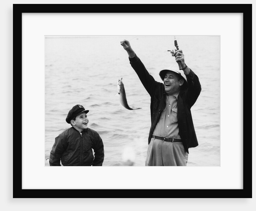 1950s 1960s Boy Son Fishing With Man Father Or Grandfather Holding Up Caught Fish On Line Laughing Having Fun by Anonymous
