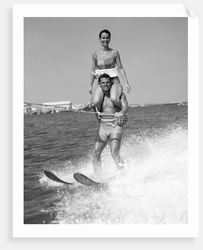 1960s Man Water Skiing With Woman In Bathing Suit Riding On Shoulders by Anonymous