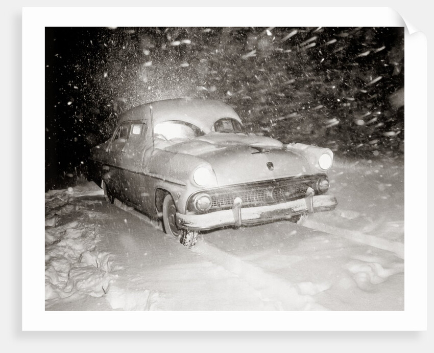1950s Snow Covered Automobile Driving On Road In Deepening Winter Blizzard Snow by Anonymous