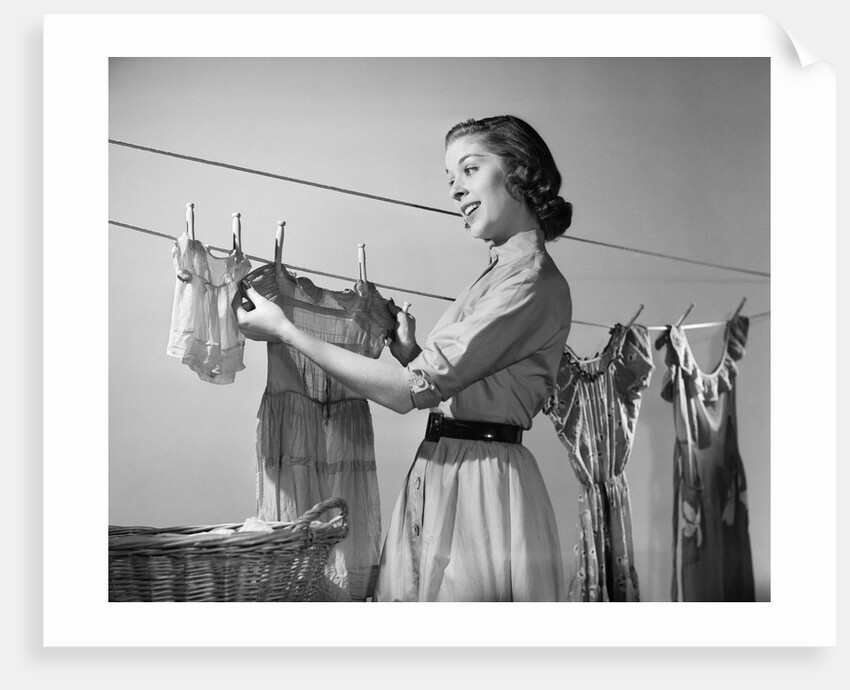 1950s Smiling Woman Housewife Hanging Wash Child Dress On Clothesline To Dry by Anonymous