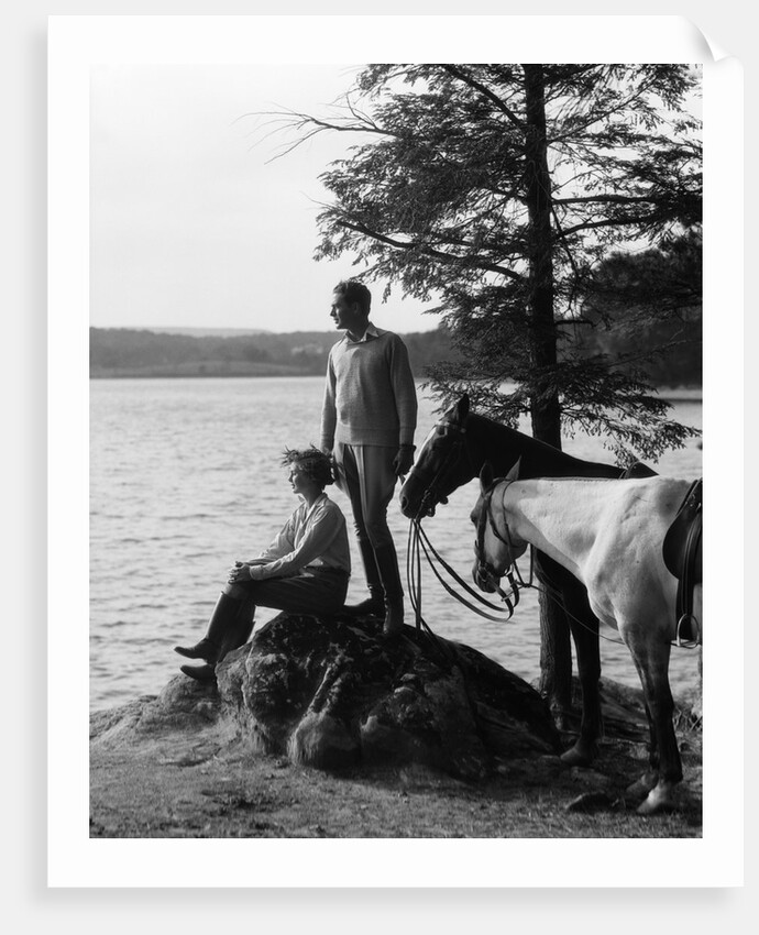 1930s Man Standing On Rock Lakeside Holding Reins Of Two Horses With Woman Seated Beside Looking Off To Side by Anonymous