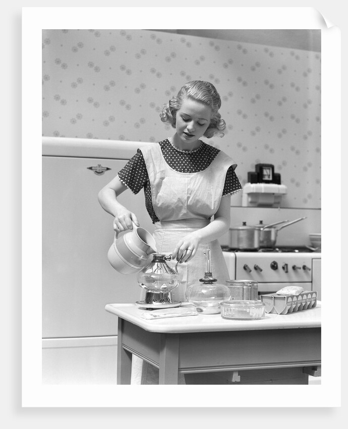 1930s Woman In Kitchen Wearing Apron Making Breakfast Pouring Water Into Coffee Pot by Anonymous