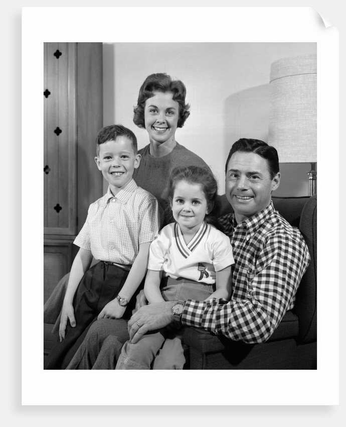 1960s Family Sitting On Couch Smiling Looking At Camera by Anonymous