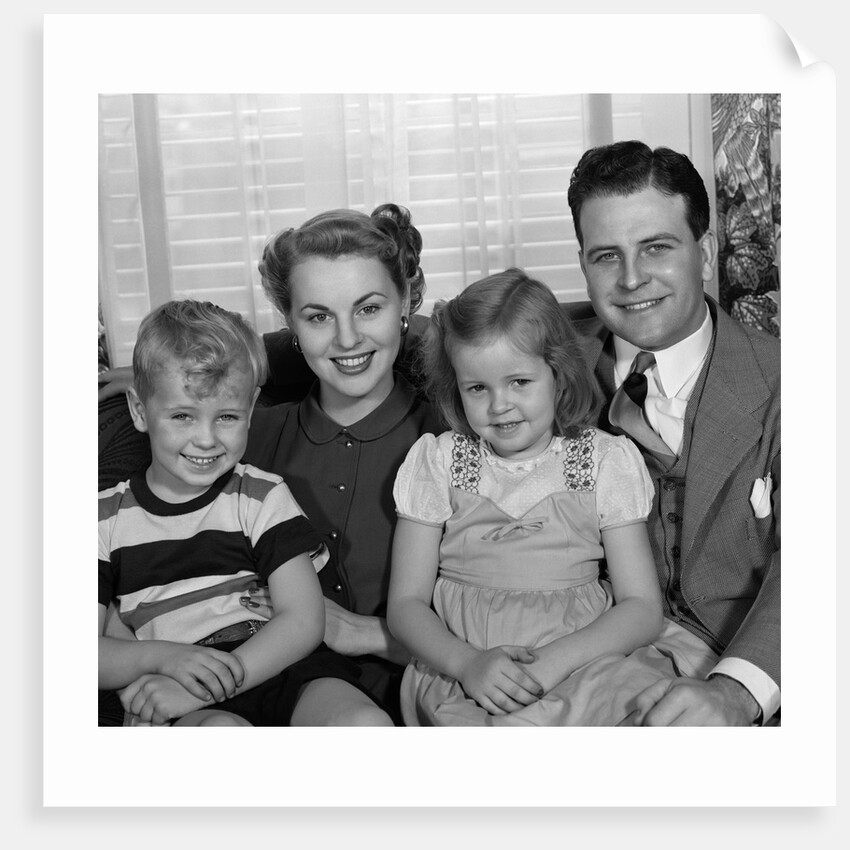 1940s 1950s Portrait Of Smiling Family Man Woman Boy Girl Sitting On Sofa Looking At Camera by Anonymous
