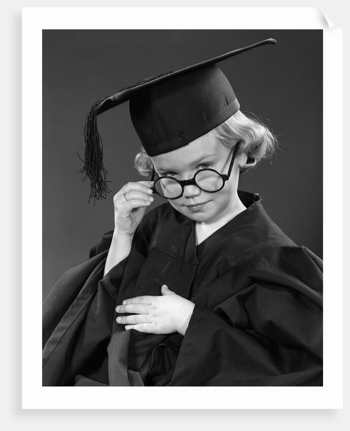 1950s Little Blond Girl Wearing Scholarly Glasses Graduation Cap And Gown Looking At Camera by Anonymous