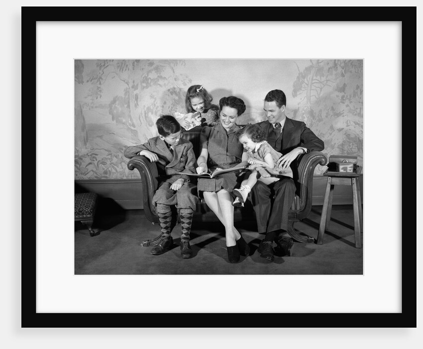 1930s 1940s Family Sitting On Couch Looking Reading Book Together by Anonymous