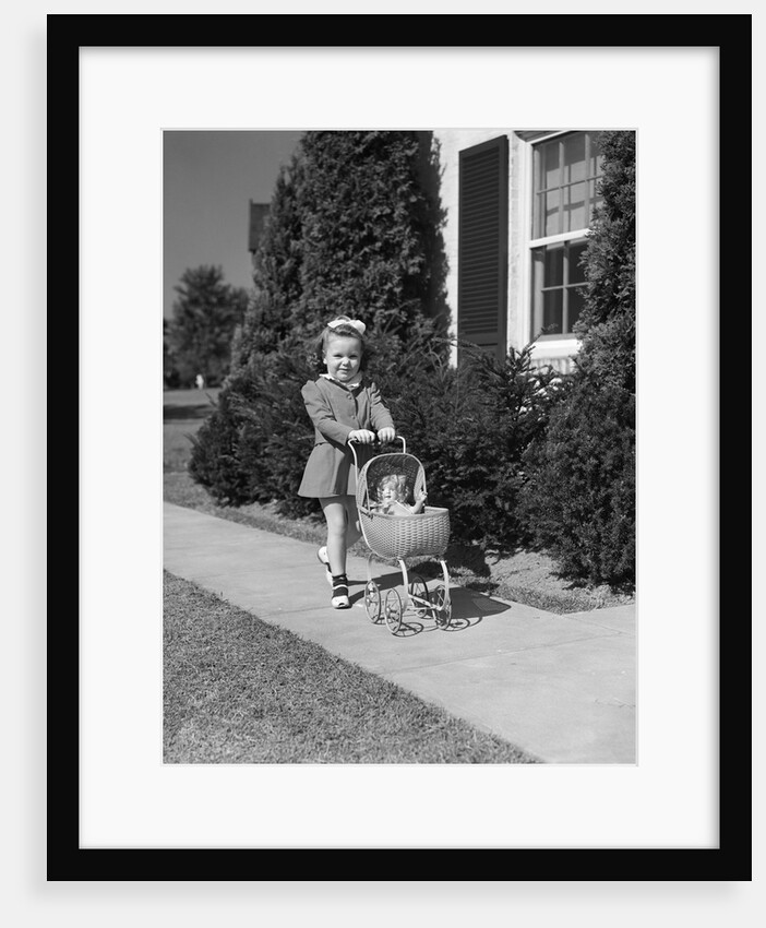1940s Little Girl Walking Pushing Her Doll In Antique Woven Wicker Stroller Looking At Camera On Sidewalk In Front Of House by Anonymous