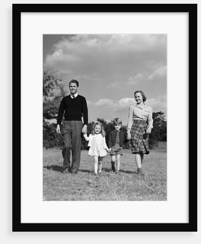 1940s Family Father Mother Son Daughter Holding Hands Together Walking On Grass by Anonymous
