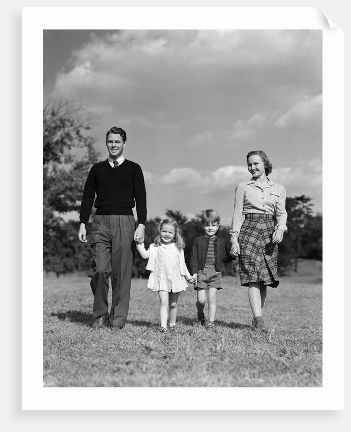 1940s Family Father Mother Son Daughter Holding Hands Together Walking On Grass by Anonymous