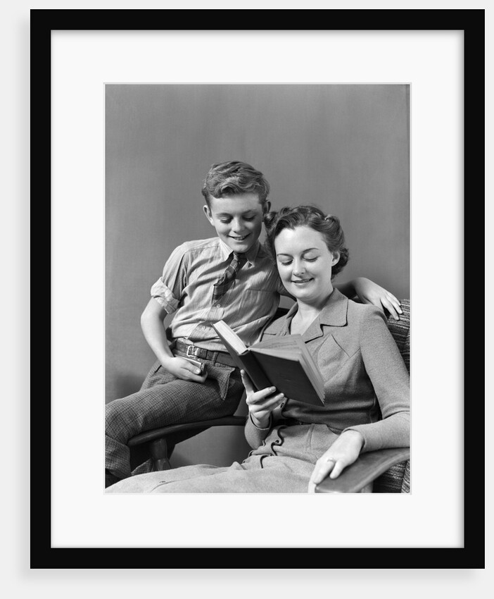 1930s 1940s Boy Son Perched On Arm Of Chair With Woman Mother Sitting In The Chair Reading A Book by Anonymous