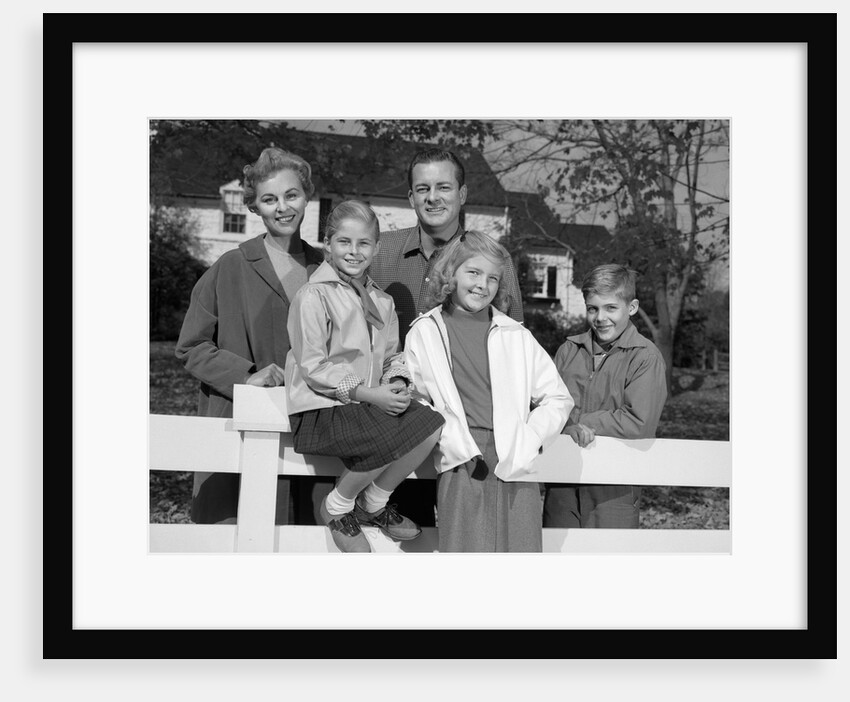 1960s Portrait Smiling Family Father Mother Two Daughters Son By White Fence In Front Of Suburban House In Autumn by Anonymous