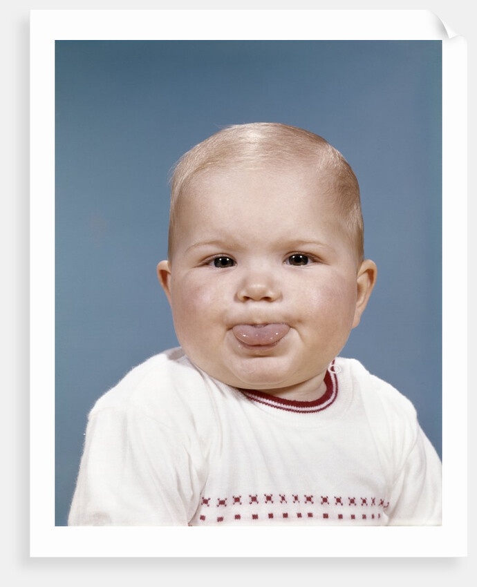 1960s Portrait Of Cute Blond Chubby Baby Looking At Camera Sticking Out Tongue by Anonymous