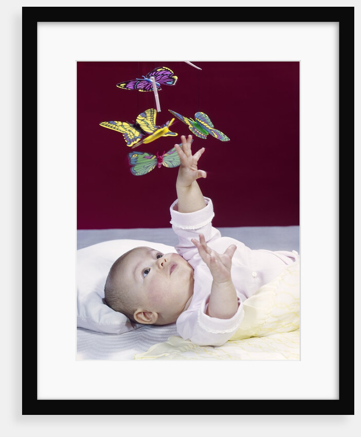 1960s Baby Reaching Up To Grab Mobile Of Butterflies by Anonymous