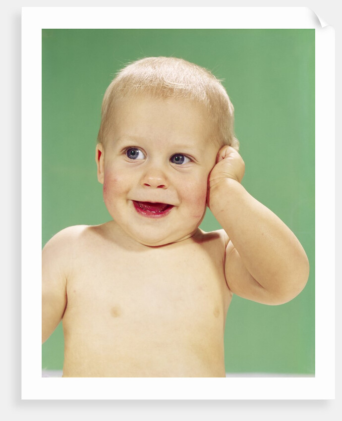 1960s Smiling Happy Baby Looking Off To The Side With Hand Touching Face by Anonymous