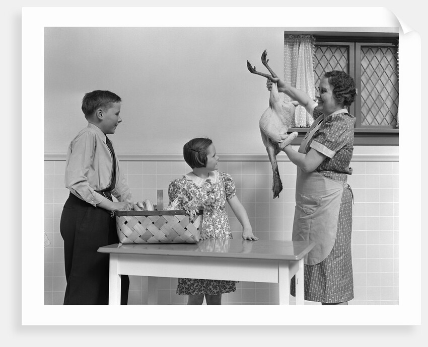 1940s housewife in kitchen showing plucked turkey to children by Anonymous
