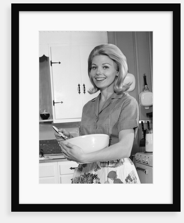 1960s 1970s smiling blond housewife in kitchen holding mixing bowl by Anonymous