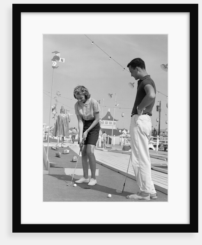 1950s 1960s teenage couple playing miniature golf by Anonymous