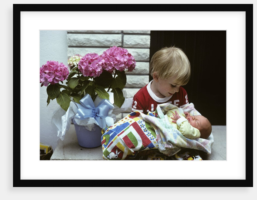 1970s boy holding a newborn baby by Anonymous
