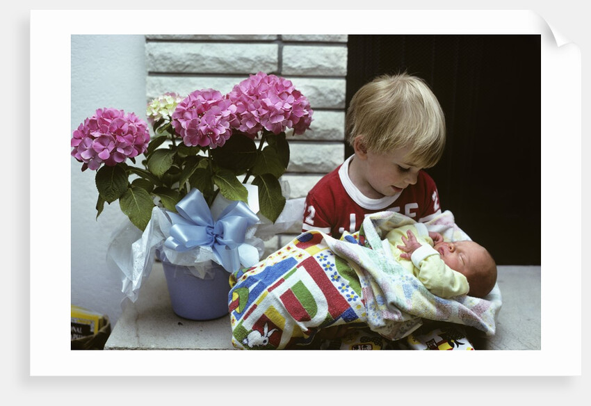 1970s boy holding a newborn baby by Anonymous