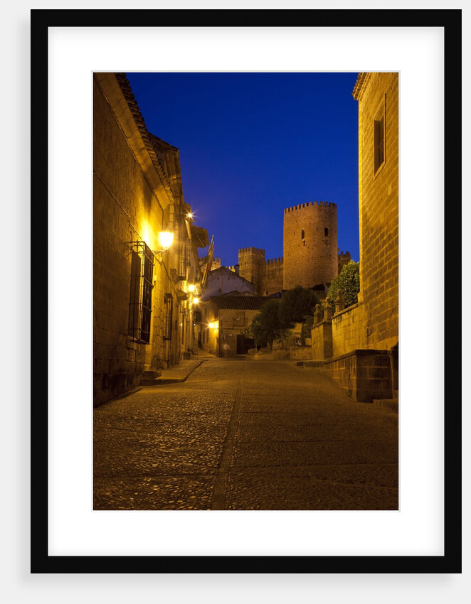 Streets of Banos de la Encina at night with the Moorish castle, named Burgalimar Castle, in the back by Anonymous