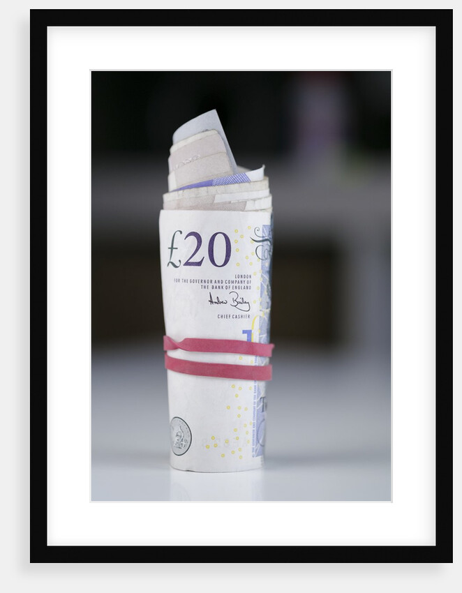 A roll of twenty pound notes on a table by Anonymous