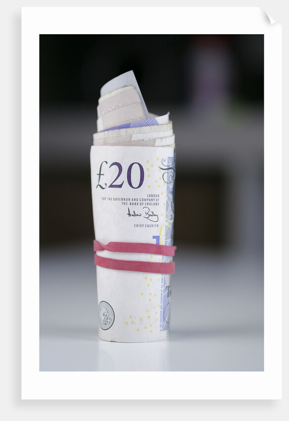 A roll of twenty pound notes on a table by Anonymous