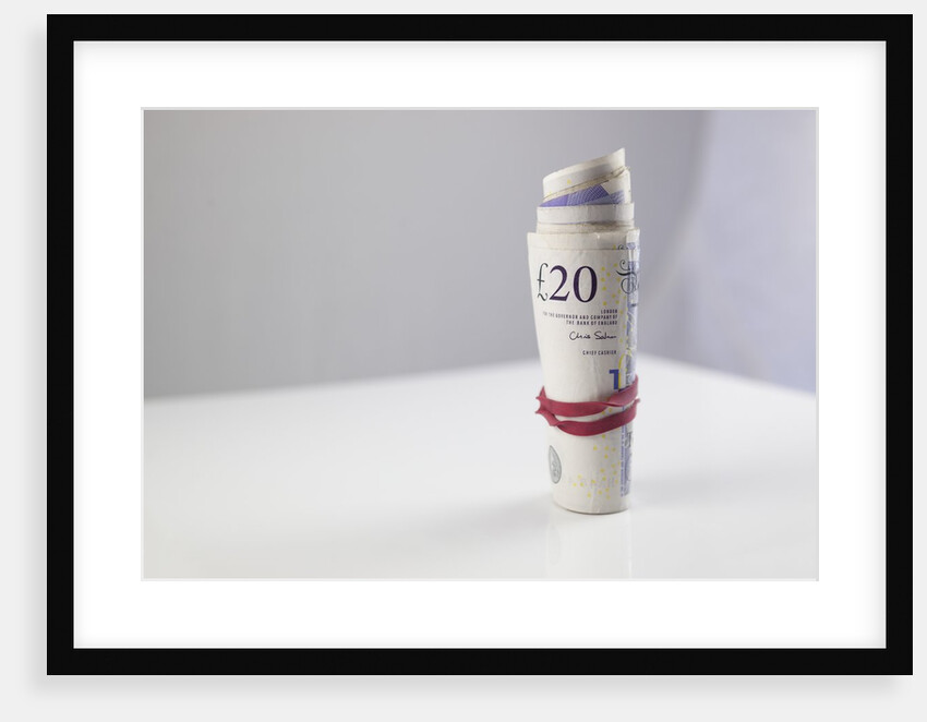 A roll of twenty pound notes on a table by Anonymous