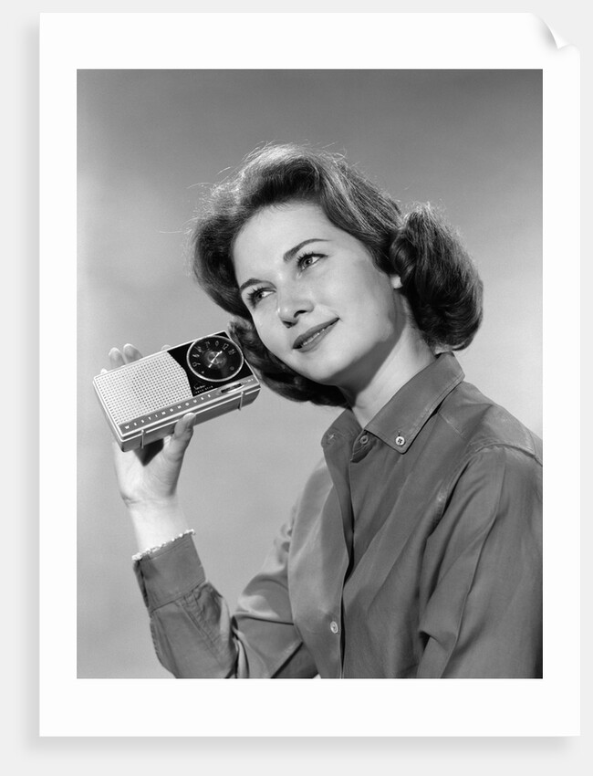 1960s smiling teenage girl listening to portable radio by Anonymous