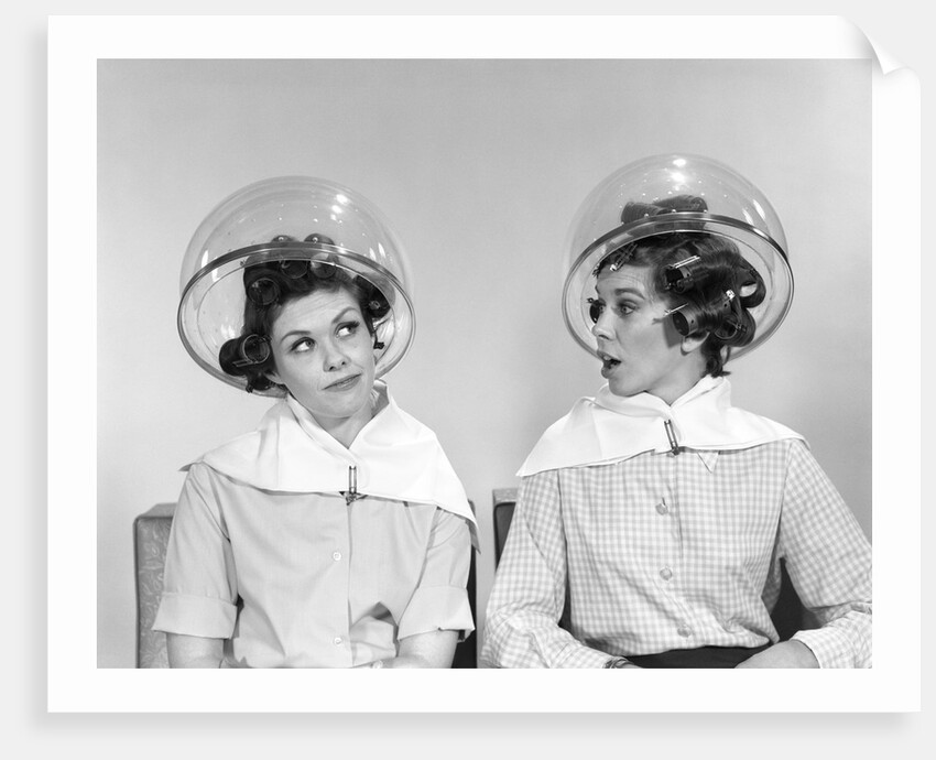 1960s two women sitting under hairdryers gossiping by Anonymous