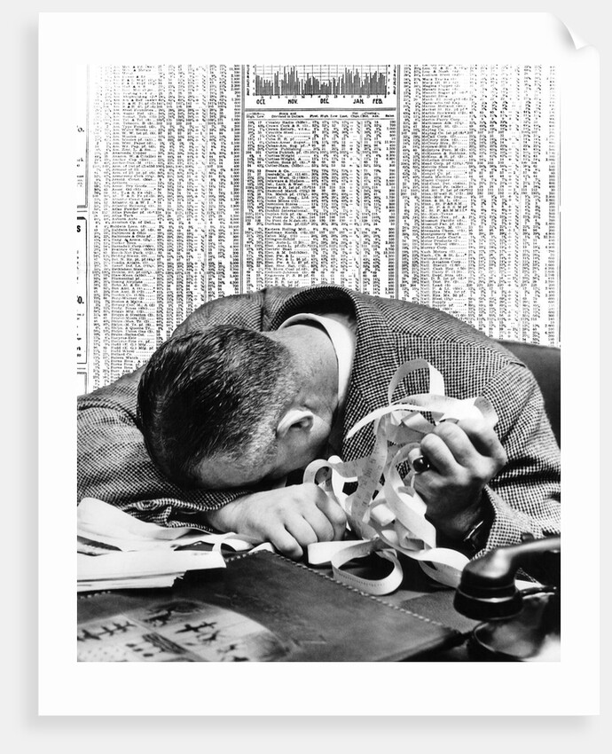 1930s man with head on his desk holding stock ticker tape by Anonymous