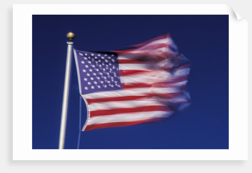American Flag is blurred with the motion of the wind against the blue sky by Anonymous