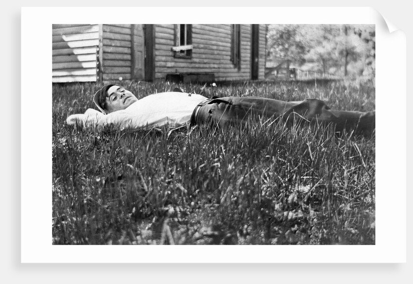 Young man lays in the grass, ca. 1912. by Anonymous