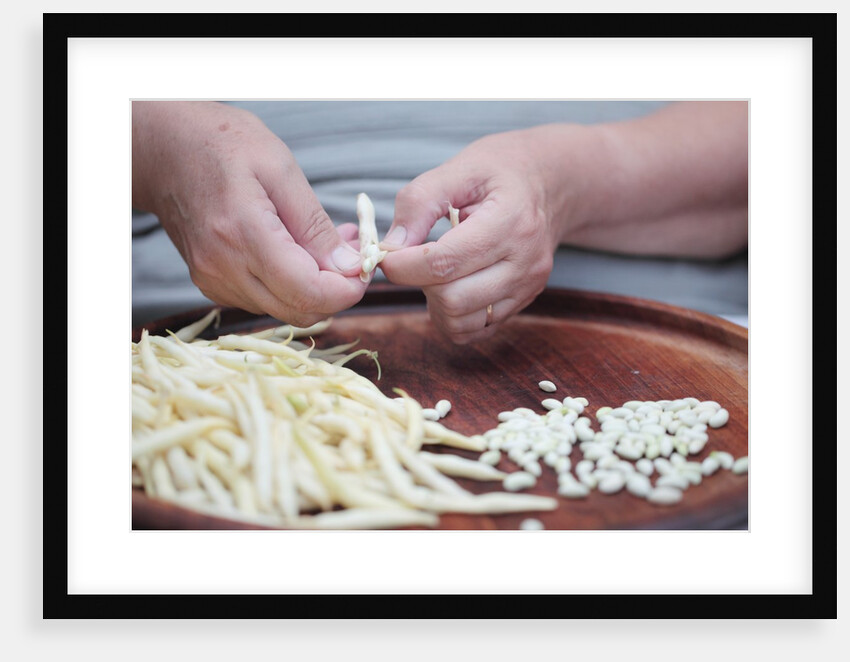 Woman selecting and separating green beans from pods by Anonymous