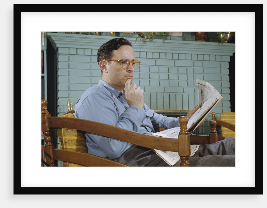 Pensive Man Reading Newspaper in Living Room by Anonymous