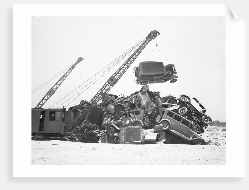 Crane Stacking Up Old Cars to be Burned in a Bonfire by Anonymous