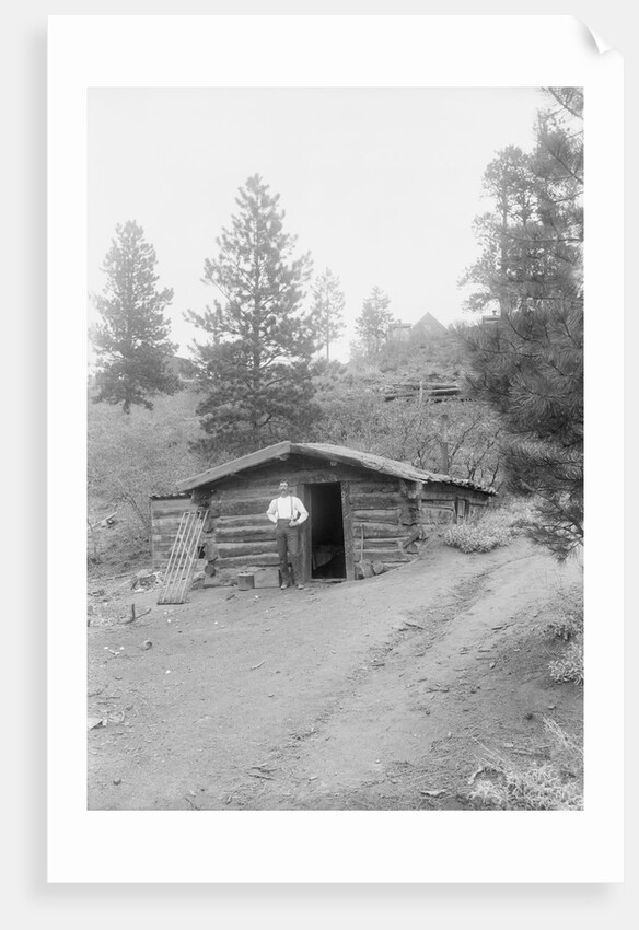 Man Standing in Front of Log Cabin by Anonymous