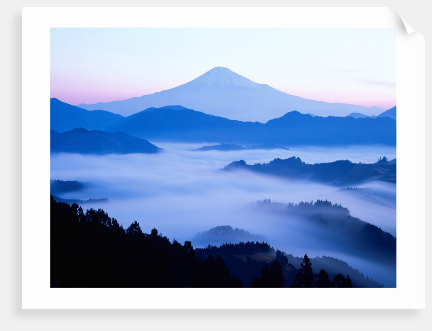 Distant view of Mount Fuji silhouetted against blue sky by Anonymous
