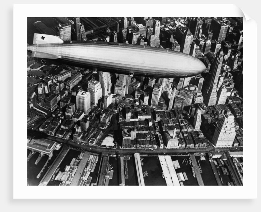 The German airship, the Hindenburg, above Manhattan, New York in 1936, on its way to its berth at Lakehurst , New Jersey, the same place where it inexplicably burst into flames the next year. by Anonymous