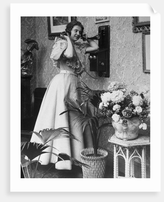 Woman Talking on Wall Mounted Telephone by Anonymous