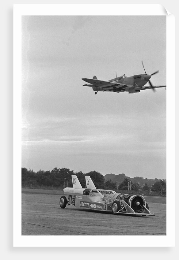 Airplane Flying Over Race Car in Action by Anonymous