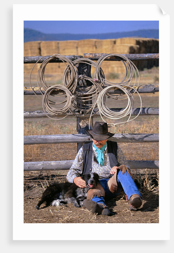 Cowboy and Dog Sitting Against Fence by Anonymous