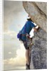 Young man rock climbing up a vertical cliff by Anonymous