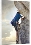 Young man rock climbing up a vertical cliff by Anonymous