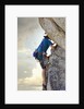 Young man rock climbing up a vertical cliff by Anonymous