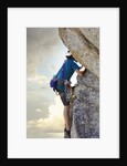 Young man rock climbing up a vertical cliff by Anonymous