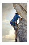 Young man rock climbing up a vertical cliff by Anonymous