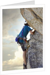 Young man rock climbing up a vertical cliff by Anonymous
