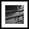 Black and white tilted view of horse grazing in meadow with wooden fence in foreground by Anonymous
