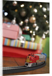 Toy train running beneath Christmas tree by Anonymous
