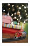 Toy train running beneath Christmas tree by Anonymous